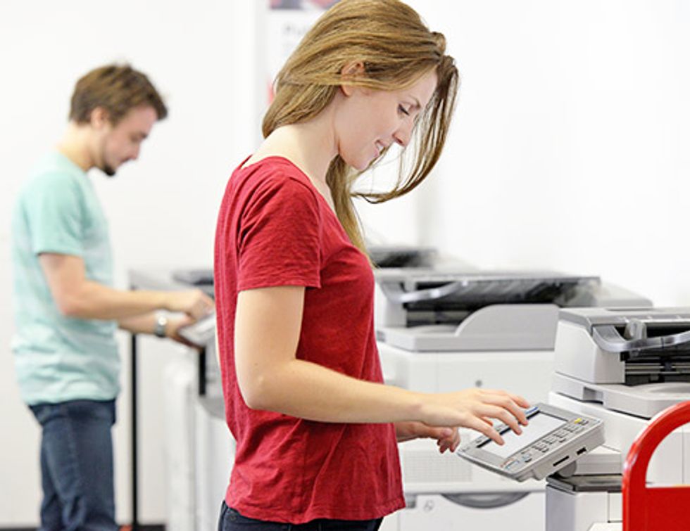      "Foto de una chica en una camisa roja trabajando en una impresora."
