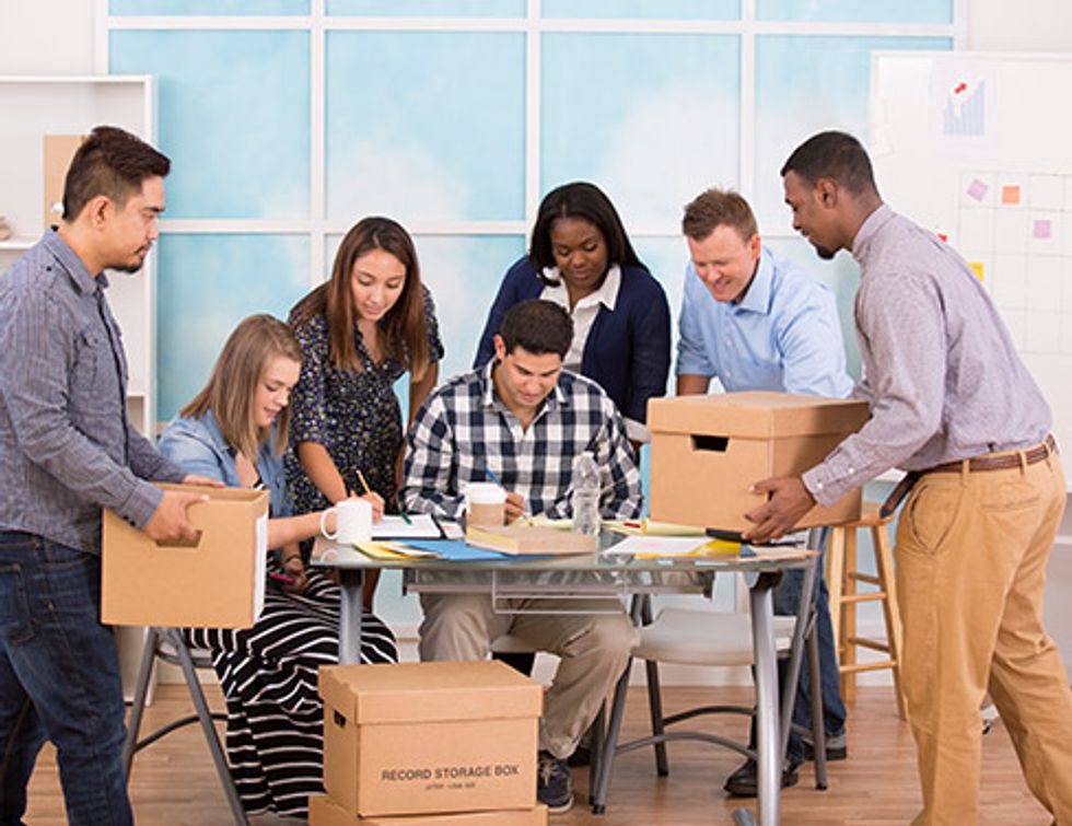 "Photo of a group of people gathered around a table with boxes and documents."