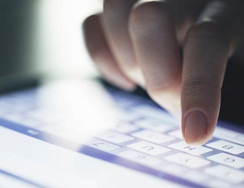 Close up image of woman typing on tablet keyboard.