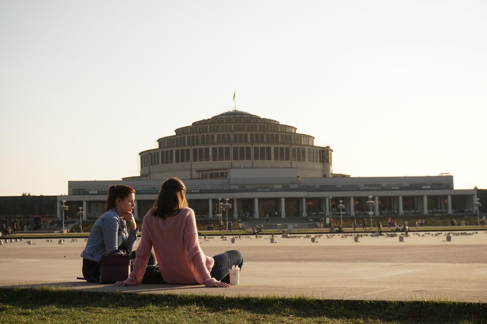 couple sitting on bench near building during daytime