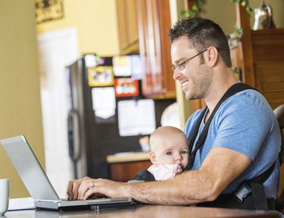 Father with baby working on a laptop at home.
